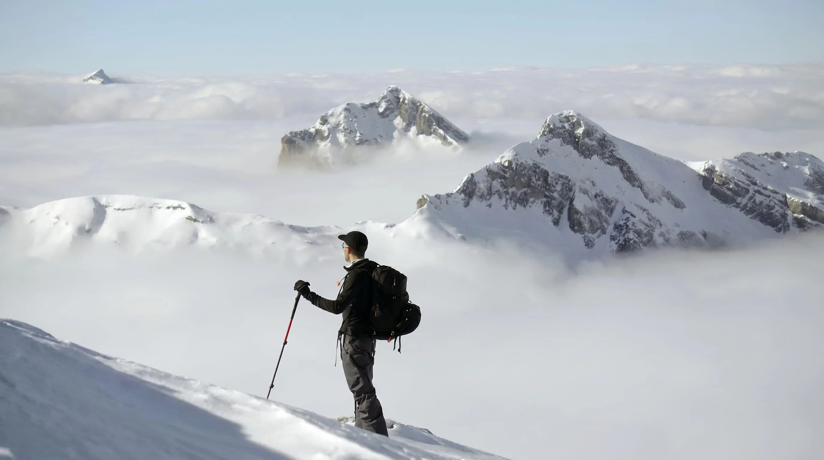 Trekker on a snow ridge above the clouds