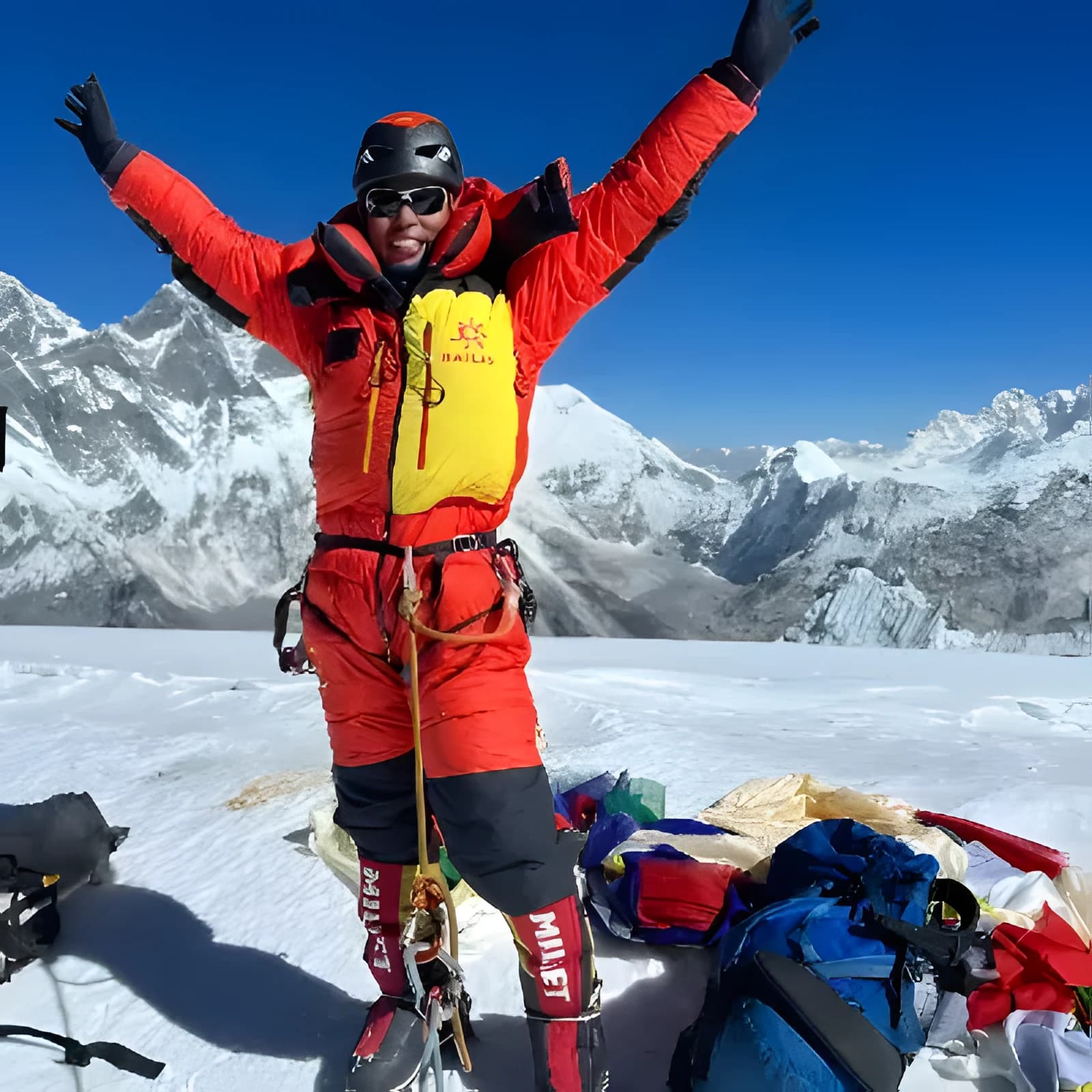 Naren Shahi Thakuri, owner of Sherpa Delights, arms raised on a snow summit