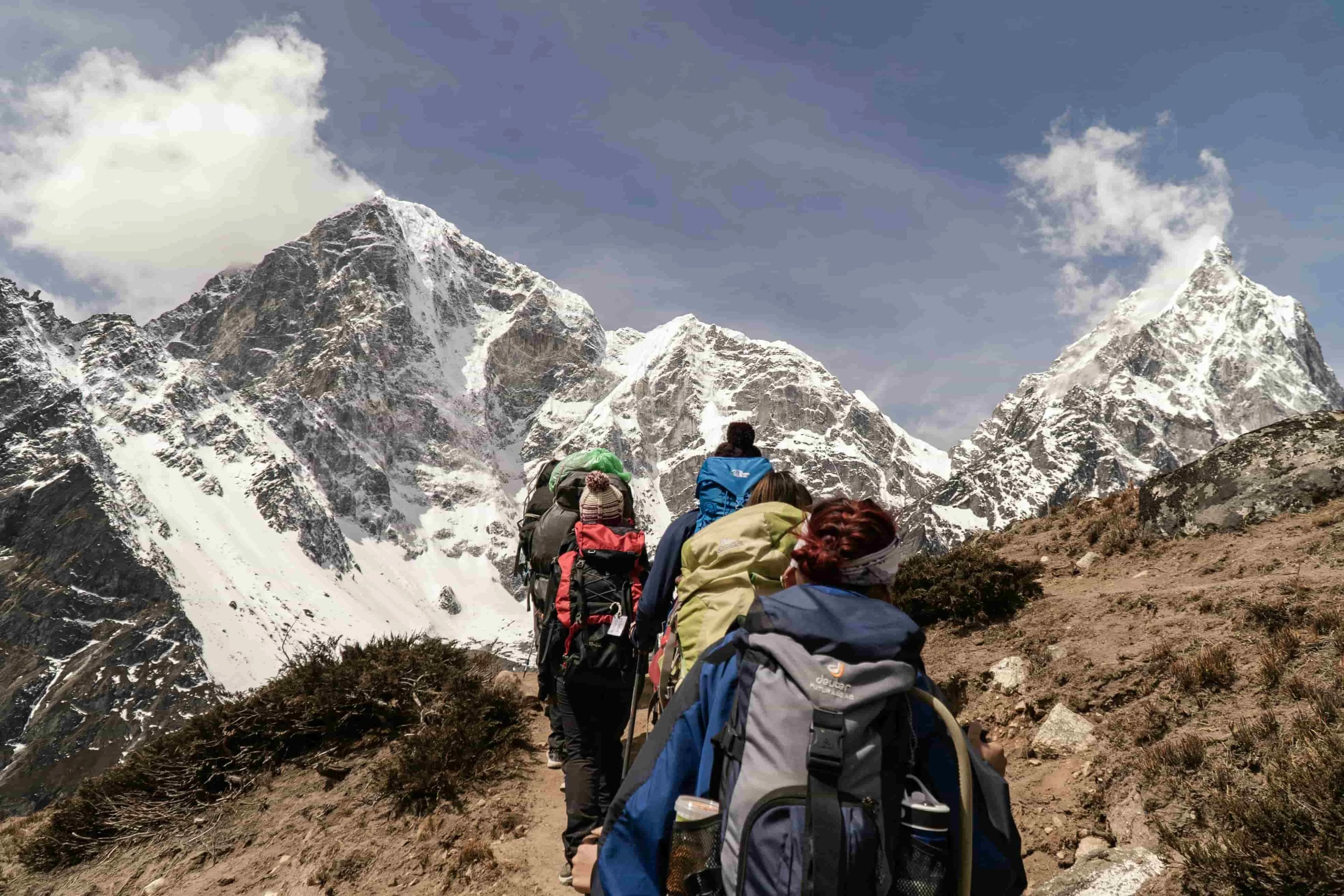 Trekkers heading up a valley toward snow peaks